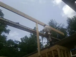Carpenter setting a ridge beam over a new addition frame — Ice Dam Removal by Roofing Brothers in Clark Mills