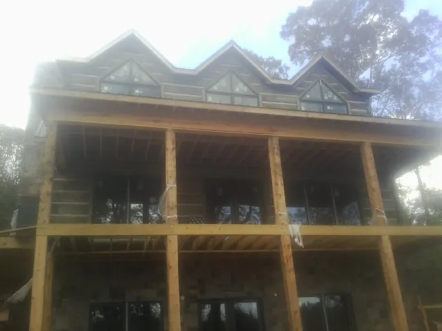 Dormers and porch framing on a large log home under construction — Roof Coating work by our crew in Clark Mills