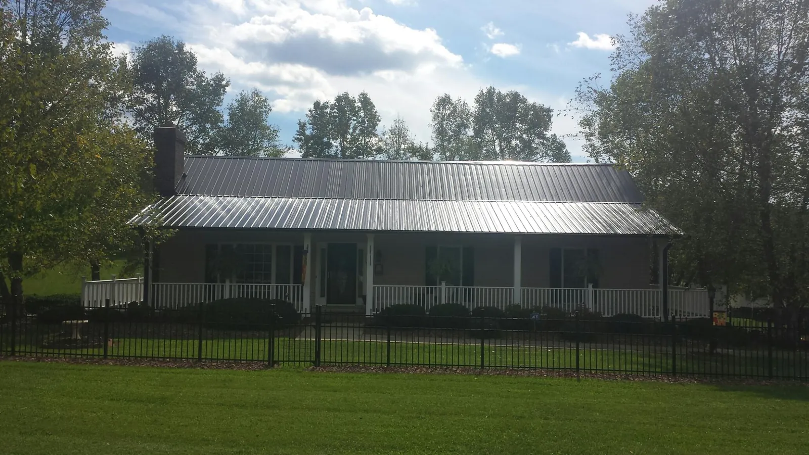 Gray metal roof on a brick ranch with a full width front porch — Gutter Guard Installation work by our crew in Clark Mills