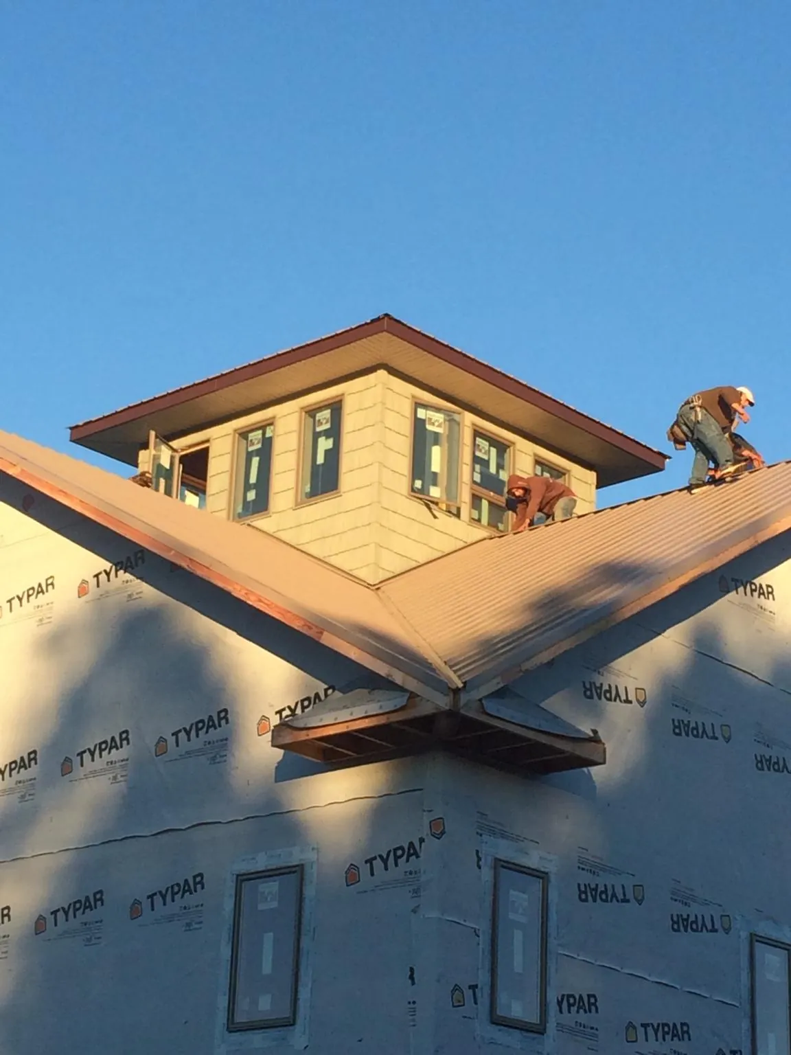 Roofers working around a rooftop cupola on a new metal roof at sunset — Roof Waterproofing in Clark Mills by Roofing Brothers